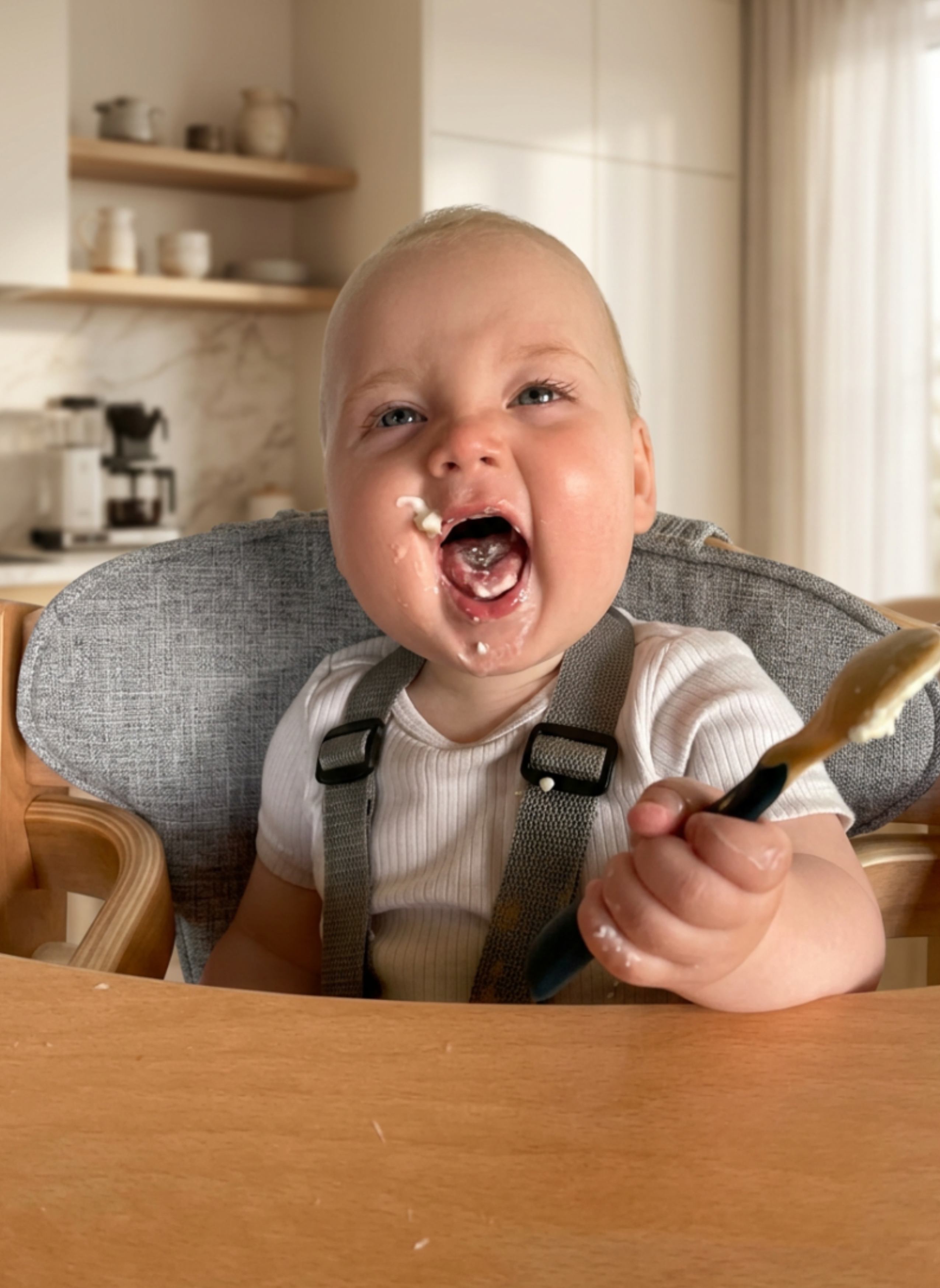 A happy baby in a high chair enjoying their first solids